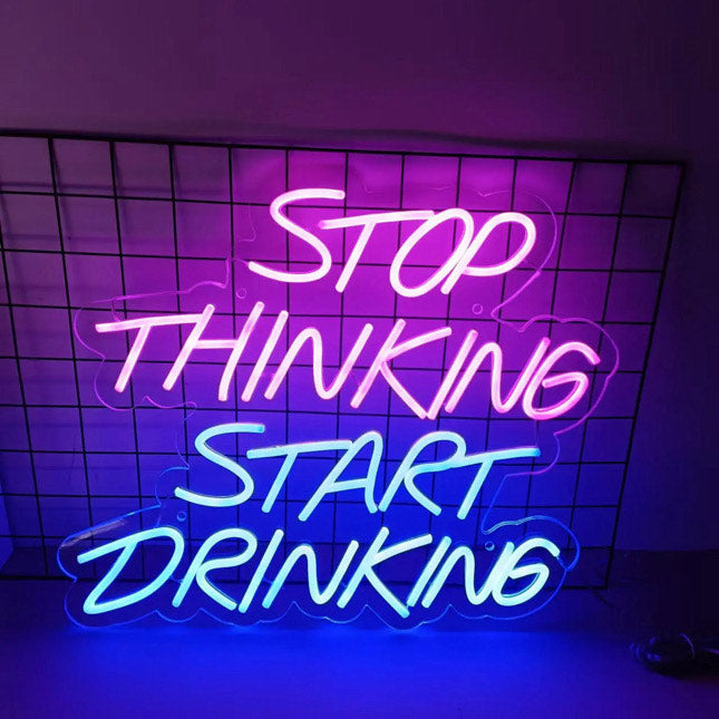 A bright bar neon sign with the text '' stop thinking start drinking''