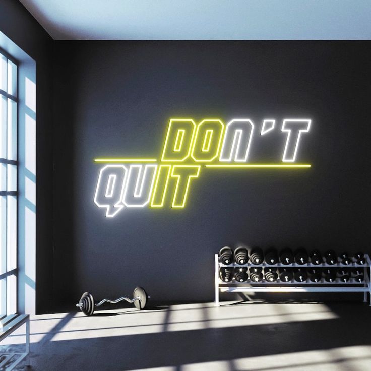 A yellow and white gym neon sign with the motivational phrase 'don't quit'