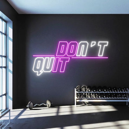 A purple and white gym neon sign with the motivational phrase 'don't quit'