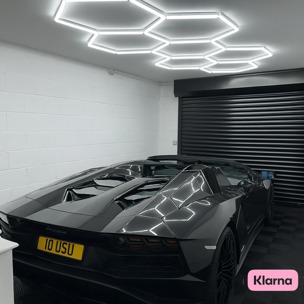 Hexagon lights mounted to the ceiling in a garage with a nice sports car parked