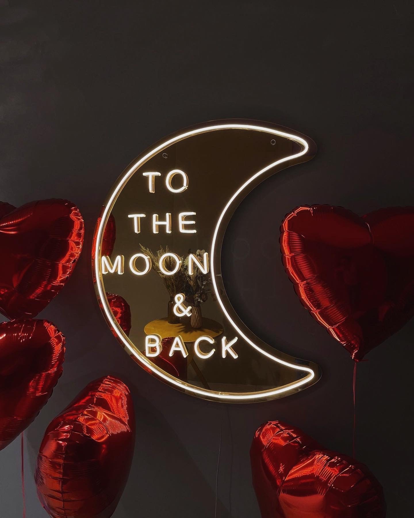 To the moon and back wedding neon sign in a cool white font with a mirrored gold acrylic background