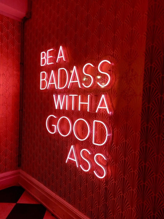 Vibrant 'Be a Badass with A Good Ass' neon sign, ideal for enhancing gym decor and motivational environments